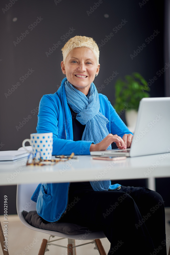 Successful businesswoman using laptop computer while sitting in modern workspace Successful businesswoman using laptop computer while sitting in modern workspace
