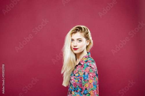 Beautiful Blonde in Colorful Shirt Looking at the Camera and Smiling on Pink Background. Pretty Girl is Posing in Studio.