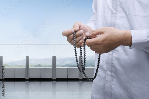 Hands of muslim praying with prayer beads in the balcony