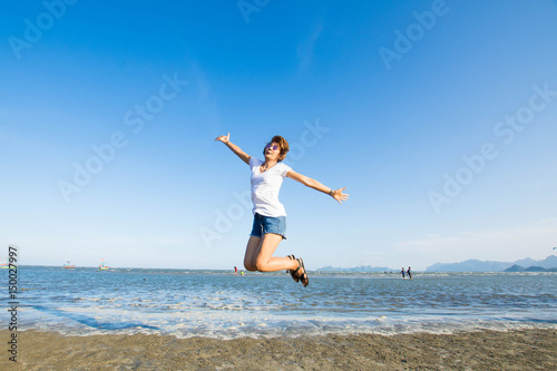 happy woman jumping on the sea at sunny day and blue sky.