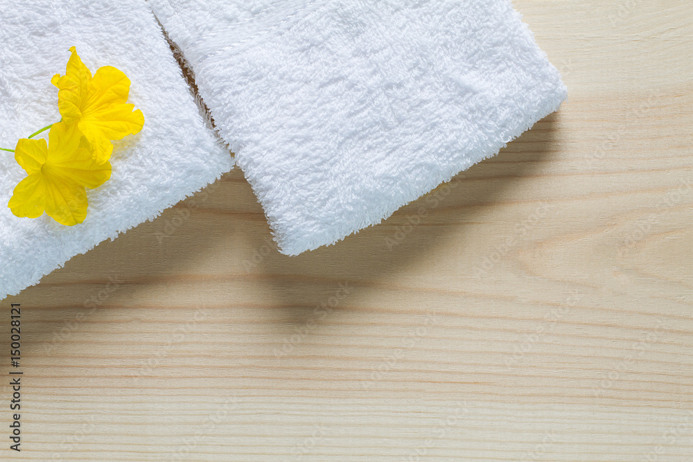 Yellow flowers on white towels with soft shadow on vintage wooden background, top view Yellow flowers on white towels with soft shadow on vintage wooden background, top view