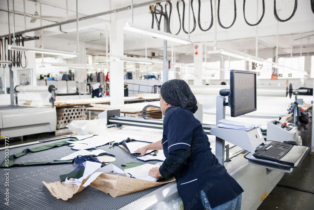 © Connect Images - Factory worker removing cut textile pattern from pattern cutting machine in clothing factory © Connect Images - Factory worker removing cut textile pattern from pattern cutting machine in clothing factory