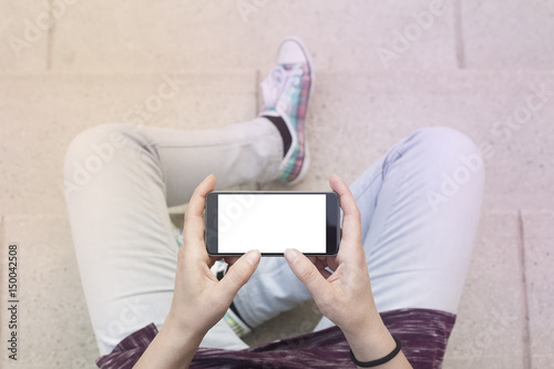Woman holding modern smartphone. Horizontal mockup. Replaceable with own design. Landscape mode, 16:9 aspect ratio.Top view.