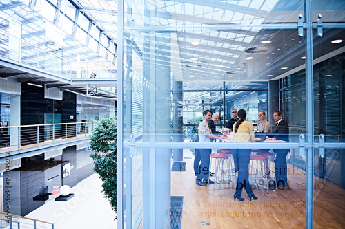 Window view of businesswomen and men having discussion in conference room