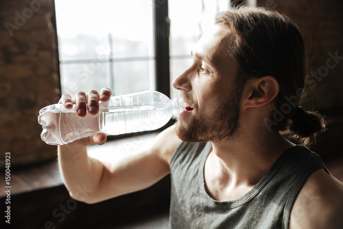 Close up of a healthy young fitness man drinking water photo