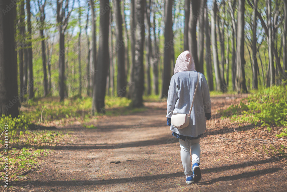 Young woman walking alone in early spring forest Young woman walking alone in early spring forest