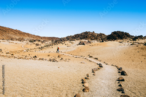 Hiker with a backpack travels through volcanic landscapes trail of the Canary Islands, Spain