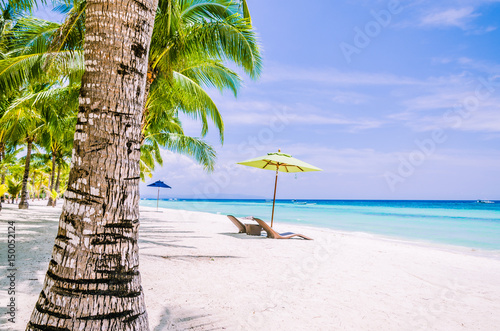Tropical beach background at Panglao Bohol island with Beach chairs on the white sand beach with blue sky and palm trees. Travel Vacation photo