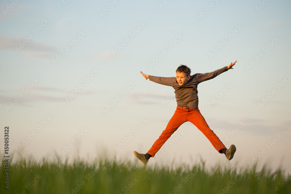 The teenager is flying over the field at sunset. The teenager is flying over the field at sunset.