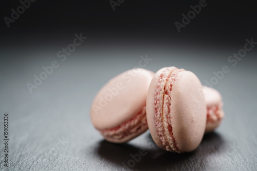 light pink macarons on slate background with copy space, shallow focus