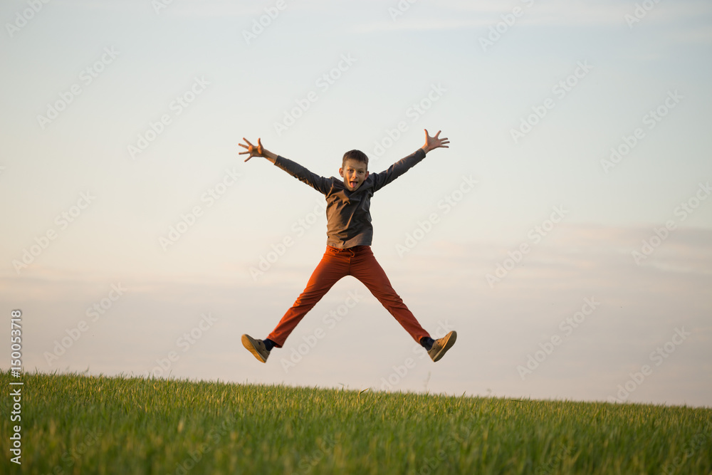 The teenager is flying over the field at sunset. The teenager is flying over the field at sunset.