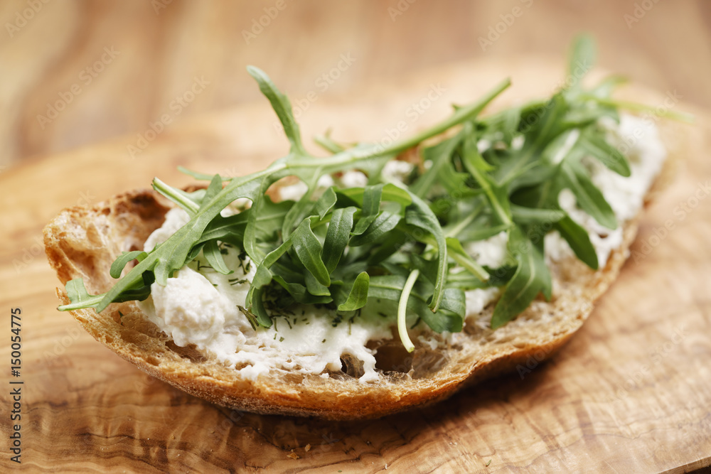 arugula on rustic bread with ricotta cheese, shallow focus arugula on rustic bread with ricotta cheese, shallow focus