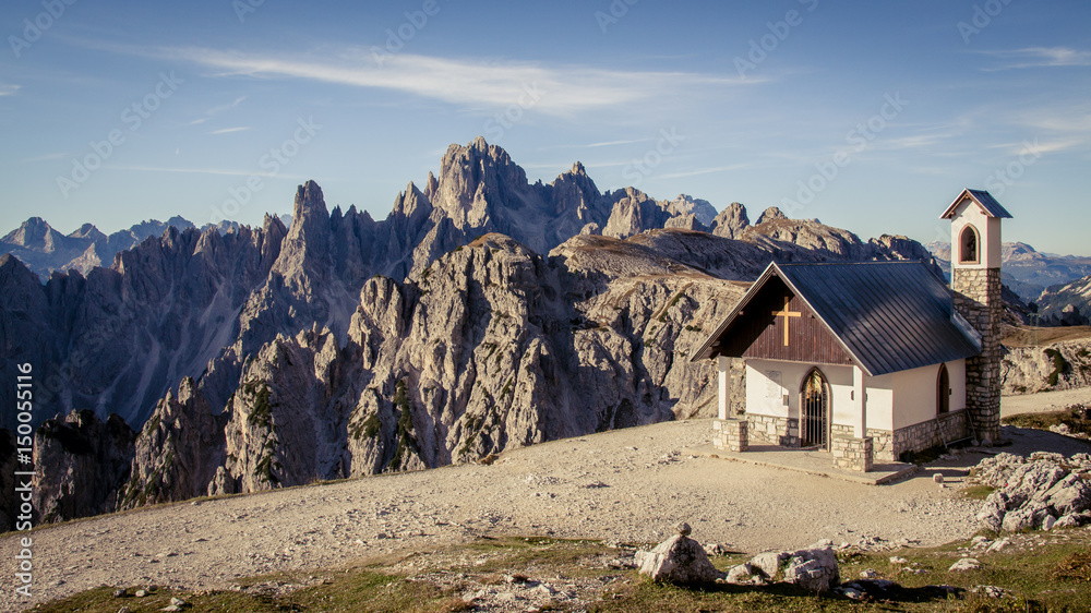 Chapel of the Alpini in the Italian Dolomites on a clear blue sky day. Mountains and Alpine scenery in the background.