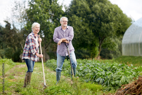 senior couple with shovels at garden or farm