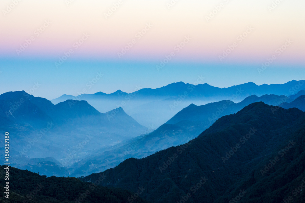 Mountain silhouettes and sunset mist over the Hoang Lien Son mountain range. On the way to Fansipan (Phan Xi Pang) - the highest mountain in Indochina located in Lao Cai Province, Vietnam