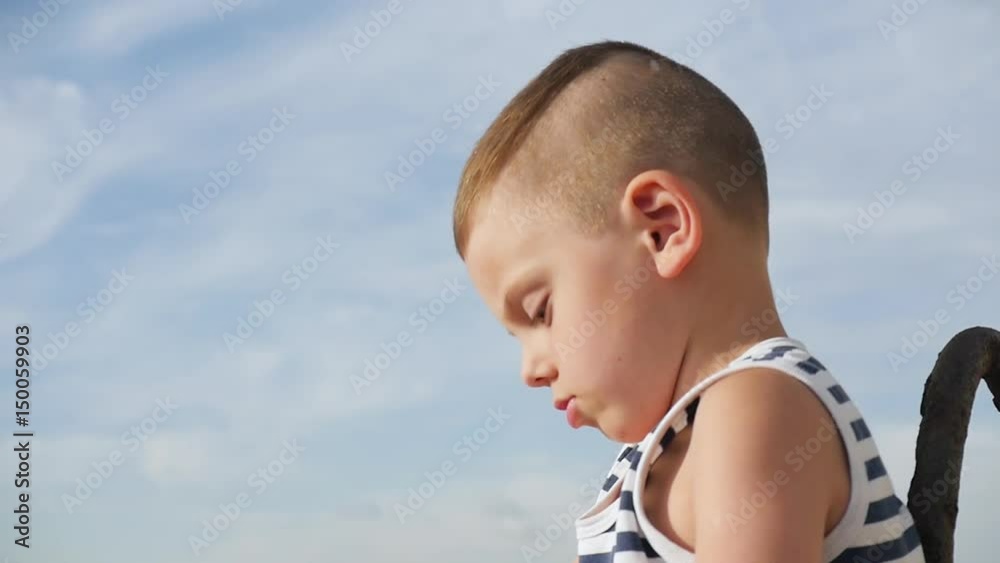 cute little boy wearing sailor stripes shirt on sky background