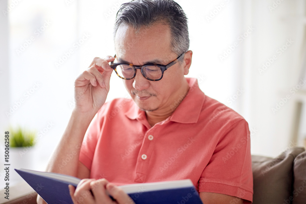 man in glasses reading book at home