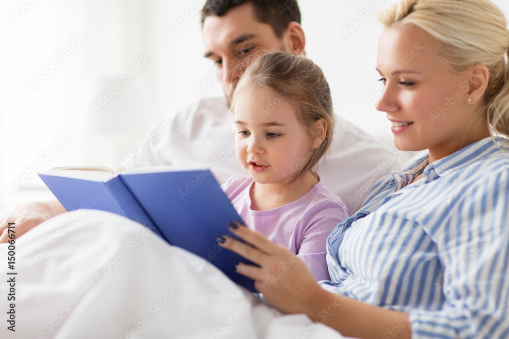 happy family reading book in bed at home