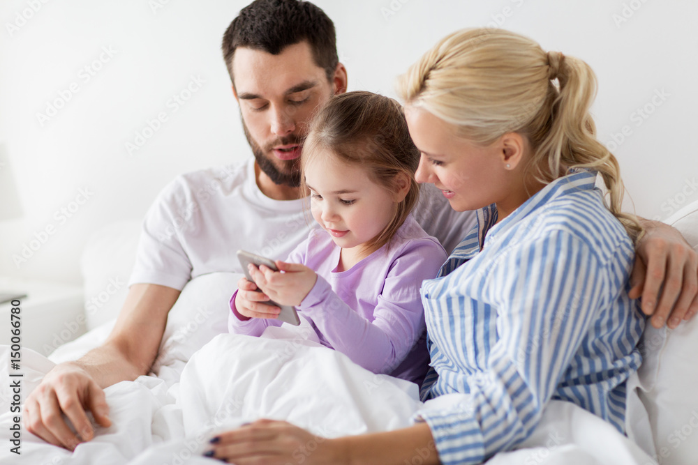 happy family with smartphone in bed at home happy family with smartphone in bed at home