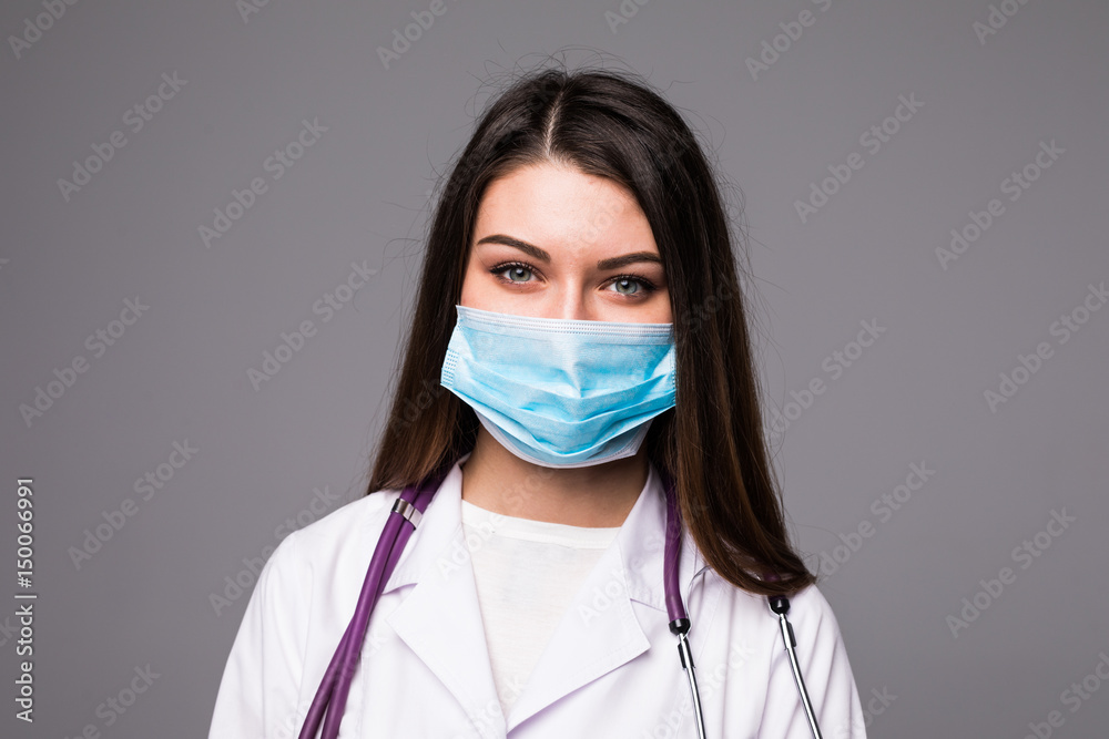Young woman doctor or nurse in cap and face mask on grey Young woman doctor or nurse in cap and face mask on grey