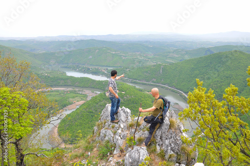 Hikers on top of a mountain enjoy the beautiful view of nature, forest and river in valley. View on meanders of Morava river from Kablar, Serbia