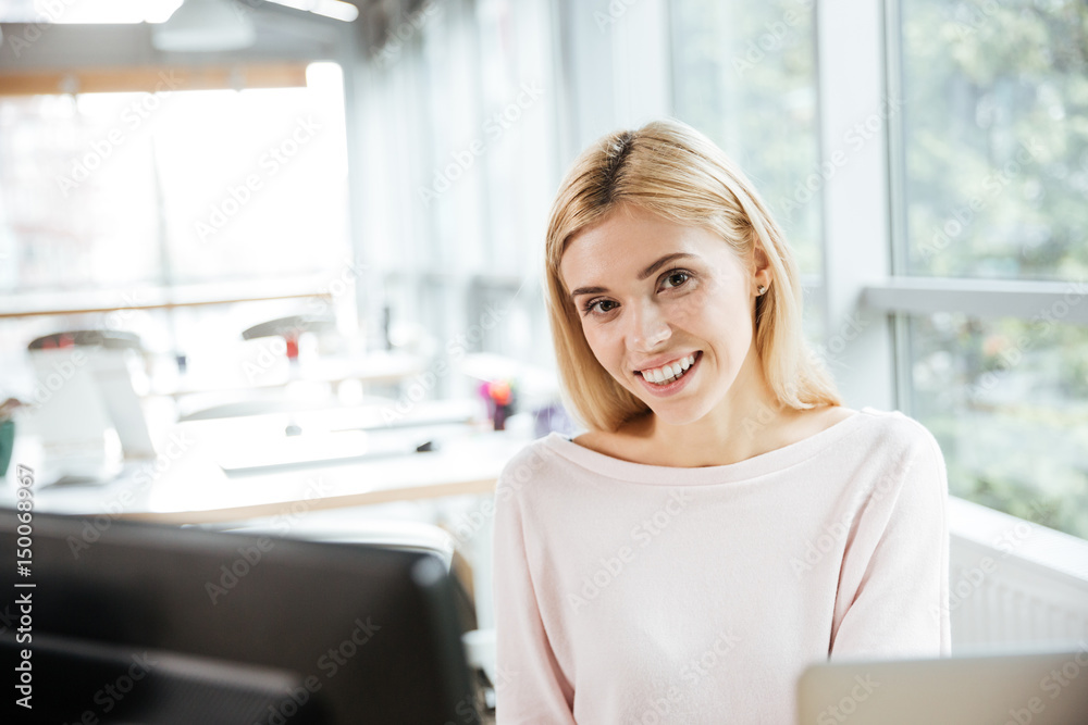 Cheerful lady sitting in office coworking using computer.