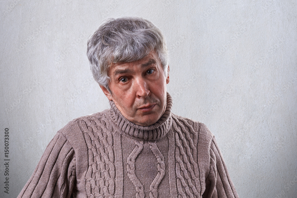 An old male with wrinkles having gray hair dressed in sweater having sympathetic expression isolated over white background. Mature man posing in studio. People and lifestyle conceppt. An old male with wrinkles having gray hair dressed in sweater having sympathetic expression isolated over white background. Mature man posing in studio. People and lifestyle conceppt.