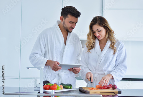 Couple in home kitchen using electronic tablet photo