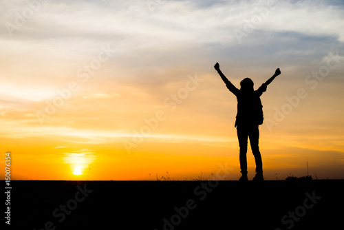 Silhouette of young woman traveler holding hand with sunset.