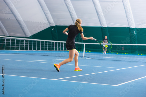 The young girl in a closed tennis court with ball