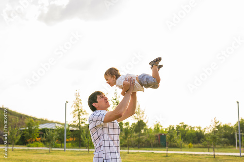 Fototapeta Naklejka Na Ścianę i Meble -  happy father holding little kid in arms, throwing baby in air. concept of happy family, fatherhood