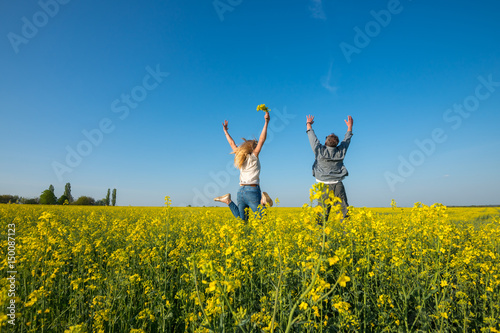 Man with a young beautiful woman are jumping and having fun in a field