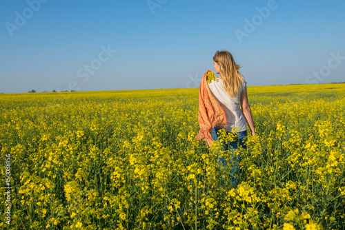Beautiful young woman, blonde with flying hair is walking through a field