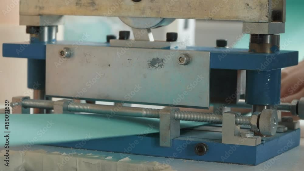 Man cuts on the machine a tape for the production of window curtains, jalousie.
Man cuts on the machine a tape for the production of window curtains, jalousie.