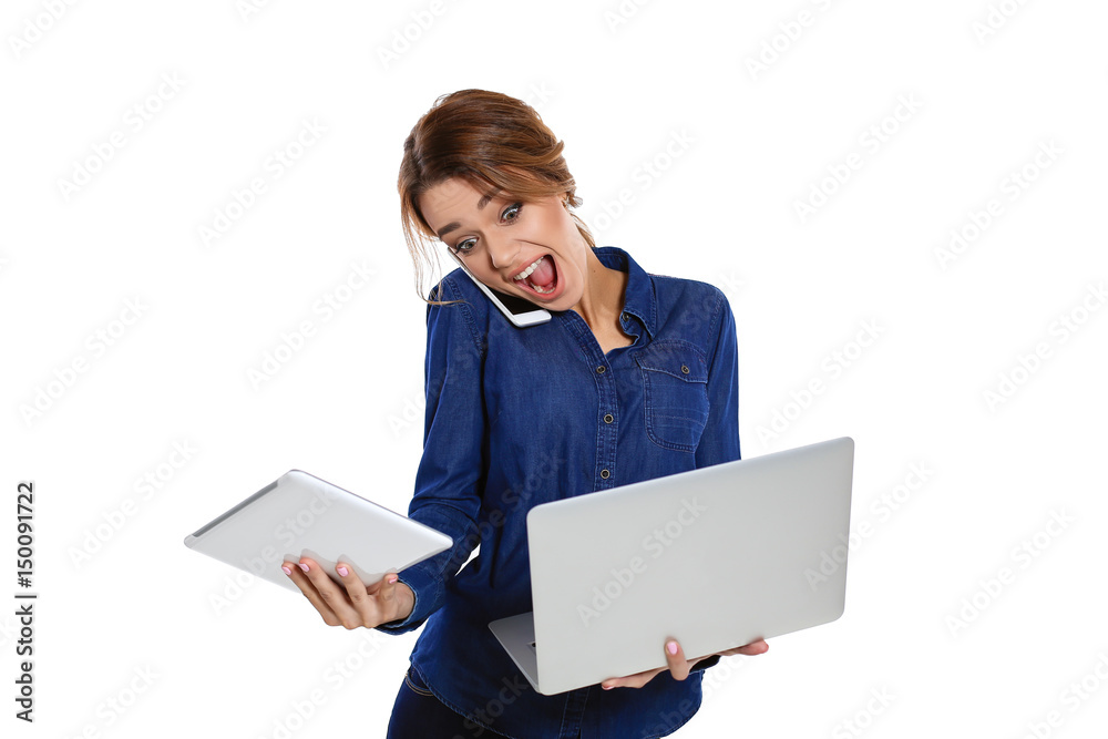 Unexpected surprise. Young woman speaks on the phone and holds a laptop in her hands screaming at him with her mouth open, standing on a white background Unexpected surprise. Young woman speaks on the phone and holds a laptop in her hands screaming at him with her mouth open, standing on a white background