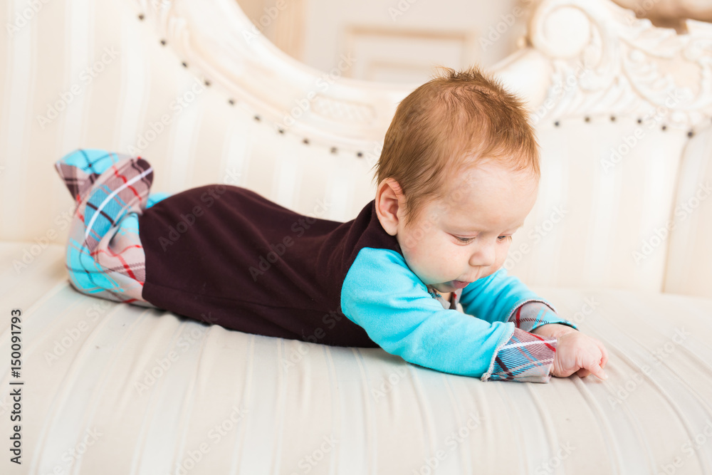 Adorable baby boy with red hair and blue eyes. Newborn child lyling in couch. Adorable baby boy with red hair and blue eyes. Newborn child lyling in couch.