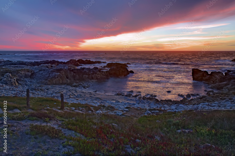 Sunset over rocks and sand at Asilomar State Beach in California