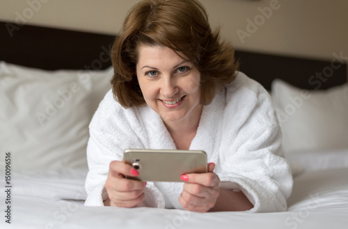 A woman in bathrobe wears telephone in hotel room