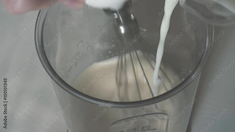 Slow mo. Hand whisk the dough with a whisk and add the milk to the mixture. Slow mo. Hand whisk the dough with a whisk and add the milk to the mixture.
