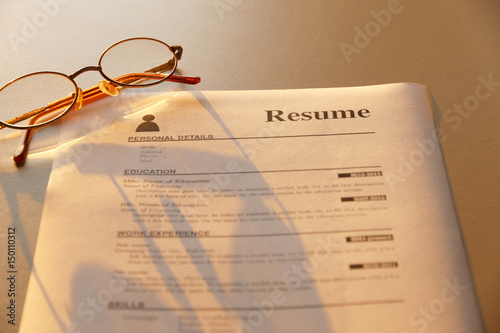 resume and glasses on wooden table.