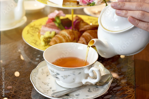 Pouring tea from vintage teapot to the cup, English Tea Time.