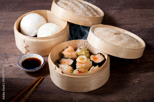 Bilde på lerret Dim sum and steamed buns in bamboo steamer on white background
