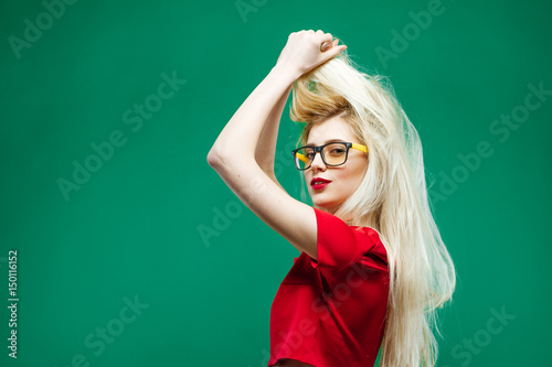 Side View of Amazing Blonde with Long Hair and Eyeglasses Posing on Green Background in Studio.