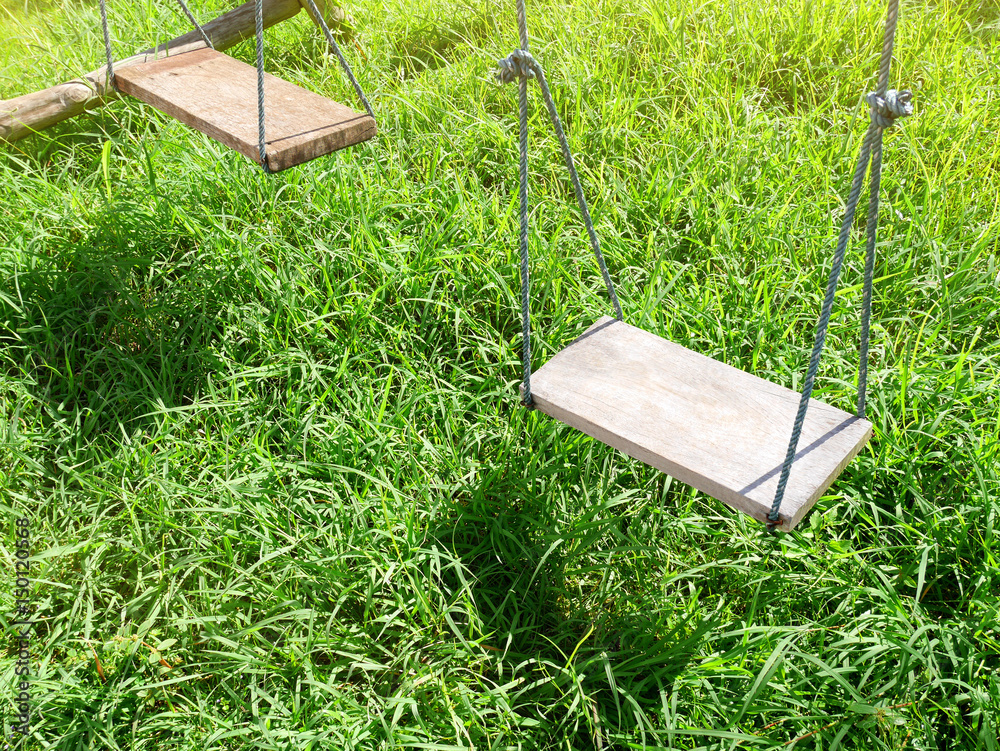 Wooden swing with green grass background in the park
