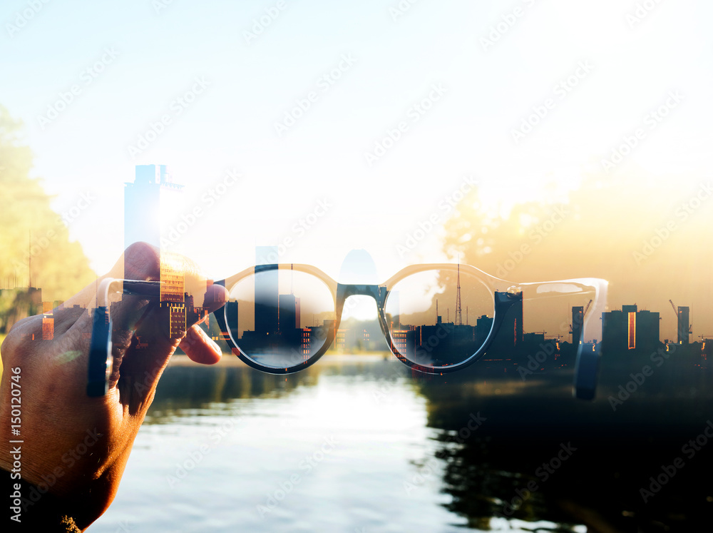 Double exposure image of Hand-held glasses scene is Cityscape focus, Business vision