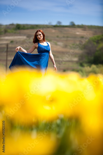 Sexy gorgeous woman in flower field in sunny summer day. Beautiful girl in springtime