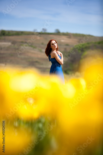 Young beautiful gorgeous woman in flower field in sunny summer day. Beautiful girl in springtime