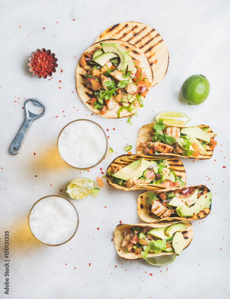 Φωτογραφία Healthy corn tortillas with grilled chicken, avocado, fresh salsa, limes, beer in glasses over light grey marble background, top view