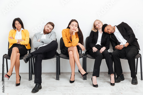 Tired colleagues sitting in office while sleeping.