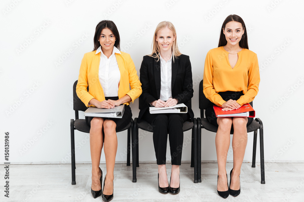 Obraz premium Wmiling women colleagues sitting with folders